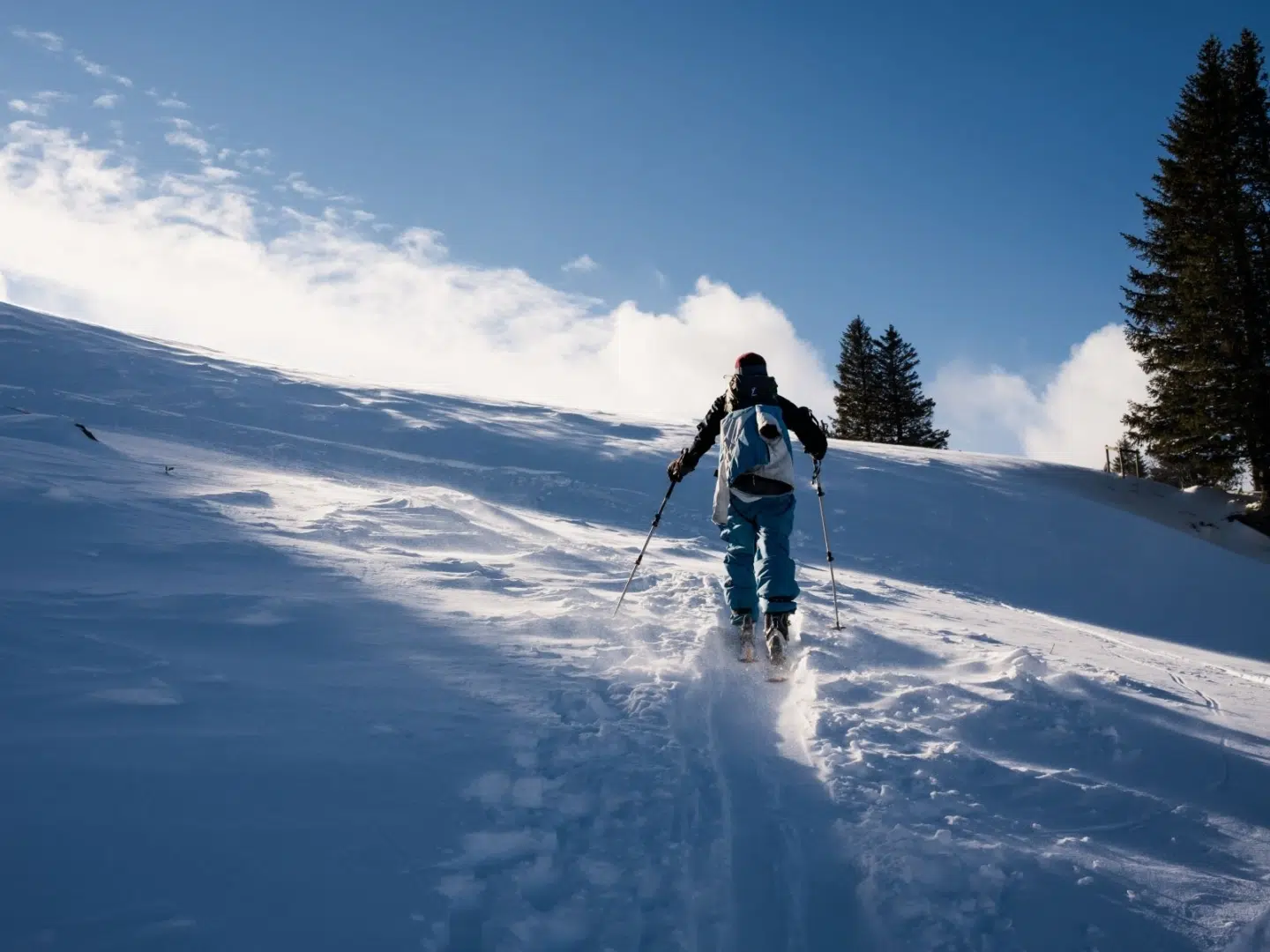 Ihr seht eine Person beim Skitourengehen im Winter.