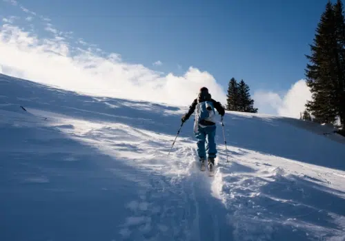 Ihr seht eine Person beim Skitourengehen im Winter.