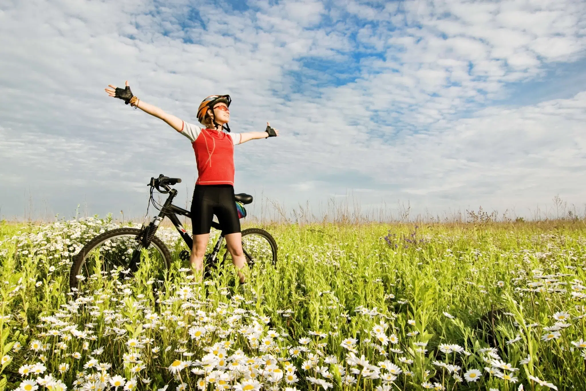 Ein Mann mit einem Mountainbike steht mitten in einer Blumenwiese und genießt während einer Pause die Natur. JUFA Hotels bietet Ihnen den Ort für erlebnisreichen Natururlaub für die ganze Familie., blumenwiese, fahrrad, fahrradhelm, familie, helm, Landschaft, Mountainbike, pause, radeln, Radfahren, radln, shutterstock, sommer, sport