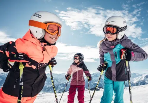 Ihr seht drei Kinder im Skigewand im Winter.