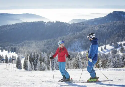 Ihr seht 2 Personen beim Skifahren am Feldberg im Schwarzwald.