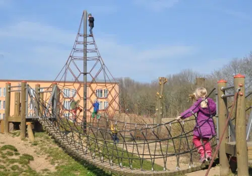 Kind geht über Hängebrücke am Spielplatz am JUFA Hotel Jülich. Der Ort für kinderfreundlichen und erlebnisreichen Urlaub für die ganze Familie.