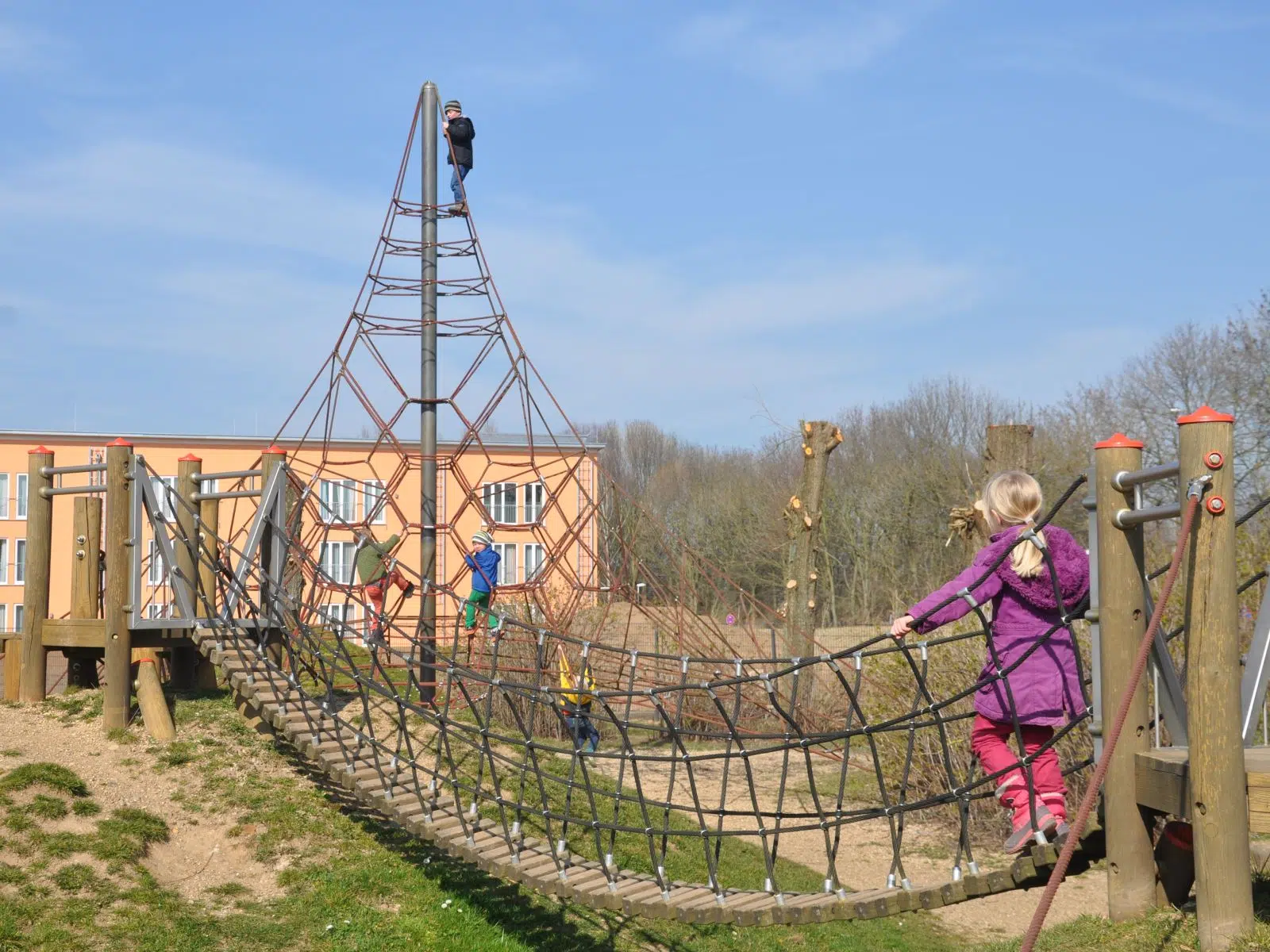 Kind geht über Hängebrücke am Spielplatz am JUFA Hotel Jülich. Der Ort für kinderfreundlichen und erlebnisreichen Urlaub für die ganze Familie.