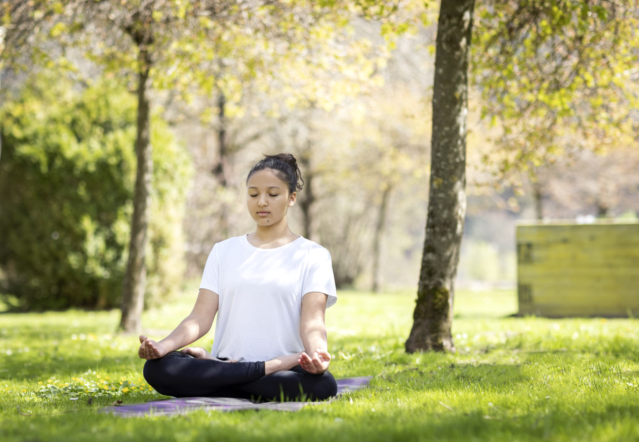 Ihr seht ein Maedchen, das sich beim Yoga im Klostergarten des JUFA Hotel Stift Gurk**** tiefenentspannt. Der Ort für erholsamen Thermen- und entspannten Wellnessurlaub für die ganze Familie.