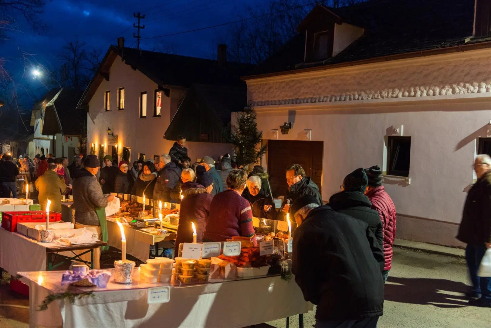 Ihr seht das Adventtreffen in Hadres, wo sich viele Besucher um den Schmankerlstand tummeln.