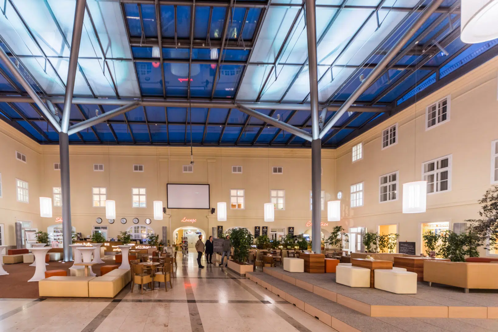 Ihr seht das Atrium im JUFA Hotel Wien City mit blauem Glasdach. JUFA Hotels bietet erlebnisreichen Städtetrip für die ganze Familie und den idealen Platz für Ihr Seminar.