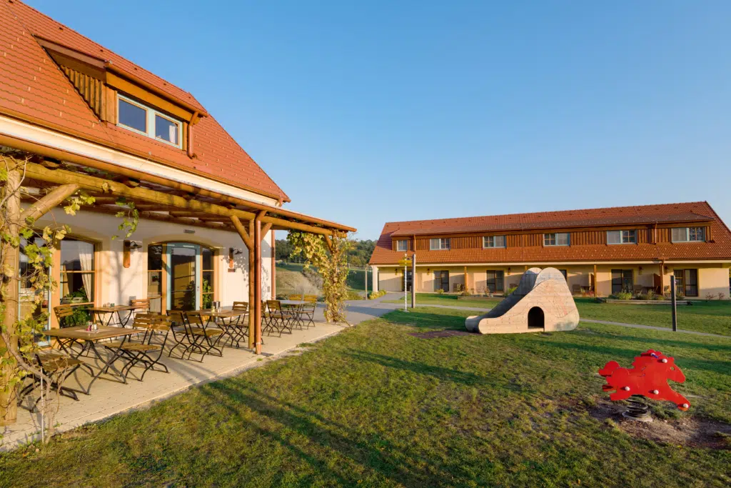 Ihr seht eine Außenansicht vom JUFA Hotel Neutal mit Terrasse im Herbst.