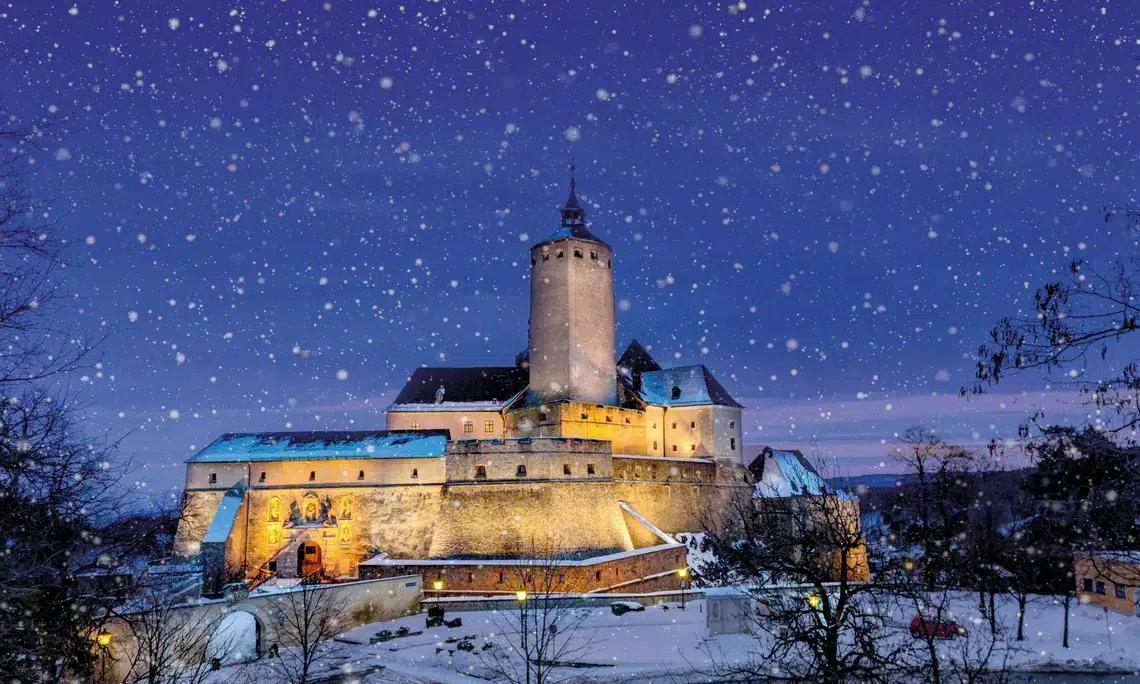 Ihr seht die schön beleuchtete Burg Forchtenstein im Schneetreiben.