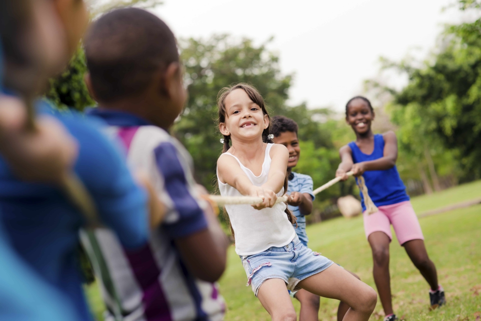 Kinder beim Tauziehen auf der Wiese. JUFA Hotels bietet erlebnisreiche Feriencamps in den Bereichen Sport, Gesundheit, Bildung und Sprachen.