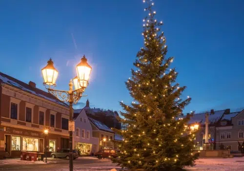 Ihr seht die Stadt Raabs an der Thaya im Waldviertel mit beleuchtetem Weihnachtsbaum im Winter. JUFA Hotels bietet erholsamen Familienurlaub und einen unvergesslichen Winter- und Wanderurlaub.