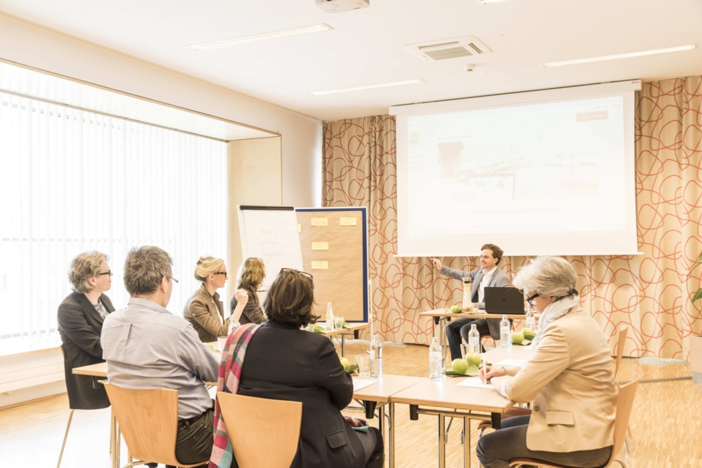 Modern ausgestatteter Seminarraum mit Seminarteilnehmern im JUFA Hotel Wien City. Der Ort für erlebnisreichen Städtetrip für die ganze Familie und der ideale Platz für Seminare.