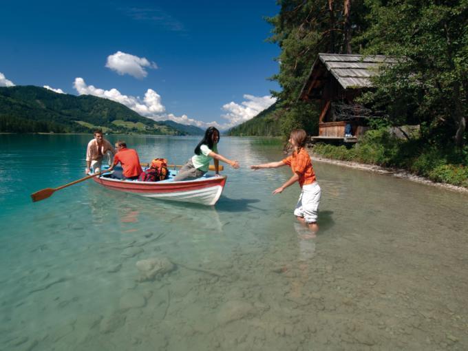 Menschen auf einer Bootsfahrt am Weissensee in Kärnten im Sommer. JUFA Hotels bietet tollen Sommerurlaub an schönen Seen für die ganze Familie.