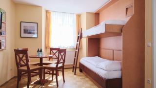 Sie sehen ein Zimmer mit Stockbett und Tisch im JUFA Hotel Meersburg